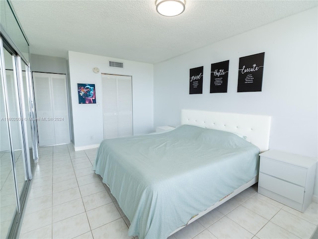 tiled bedroom with a textured ceiling and two closets