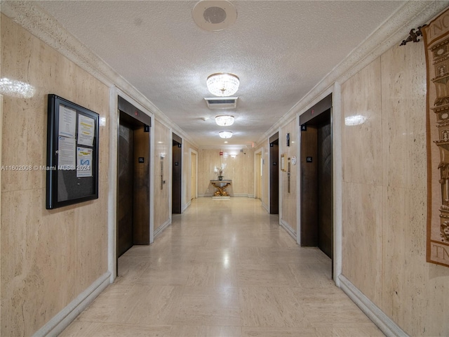 hall with elevator and a textured ceiling