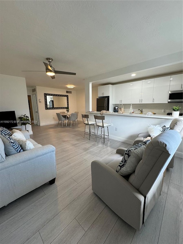 living room featuring ceiling fan and a textured ceiling