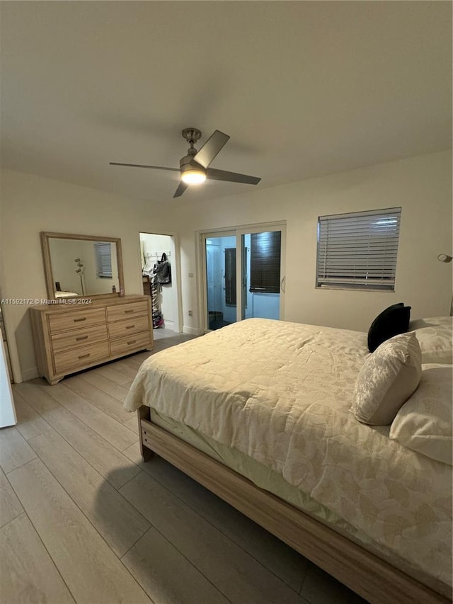 bedroom with ceiling fan, a spacious closet, and light hardwood / wood-style flooring