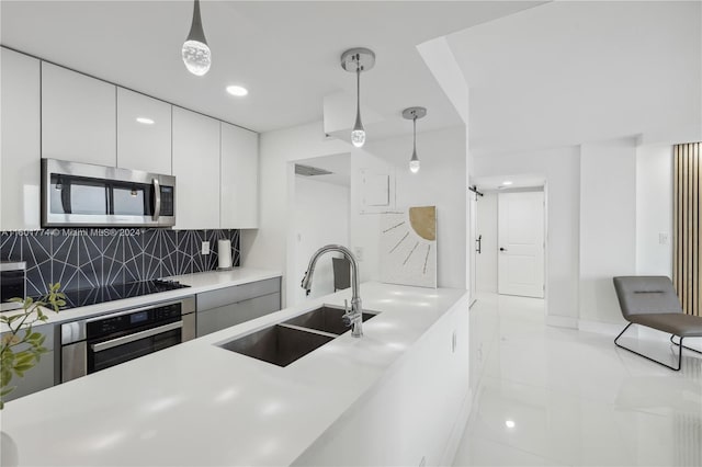 kitchen with sink, white cabinets, decorative backsplash, hanging light fixtures, and stainless steel appliances