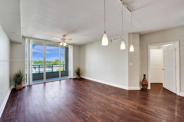 spare room with ceiling fan, dark wood-type flooring, a textured ceiling, and a wall of windows