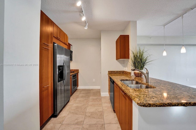 kitchen with appliances with stainless steel finishes, pendant lighting, sink, dark stone countertops, and a textured ceiling