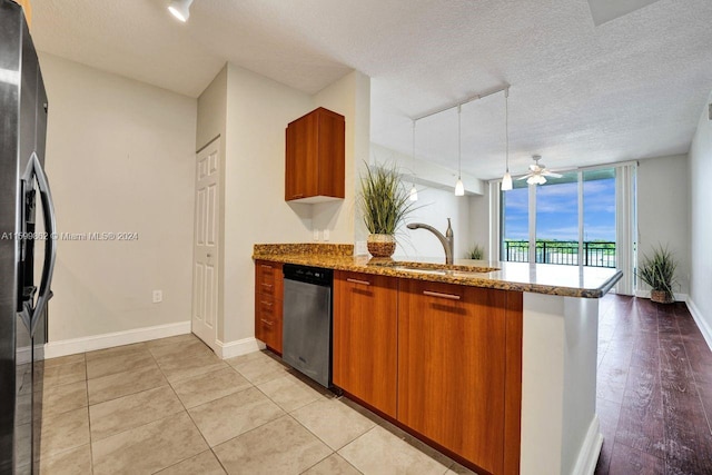 kitchen with sink, appliances with stainless steel finishes, hanging light fixtures, light stone countertops, and kitchen peninsula