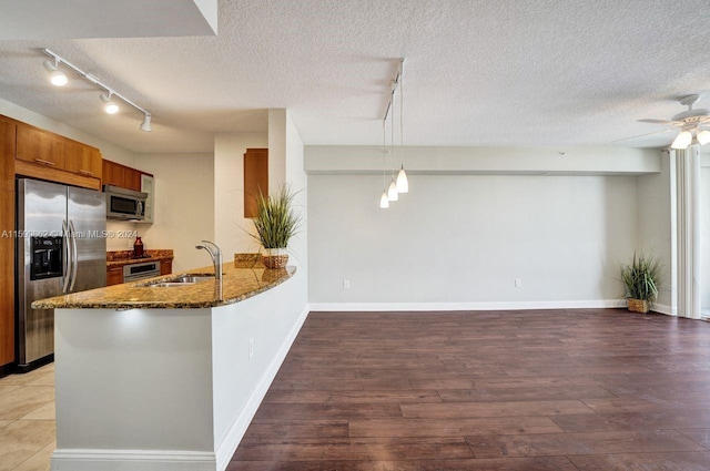 kitchen featuring sink, hanging light fixtures, light wood-type flooring, appliances with stainless steel finishes, and kitchen peninsula