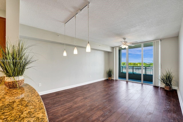 unfurnished room featuring dark hardwood / wood-style flooring, ceiling fan, floor to ceiling windows, track lighting, and a textured ceiling