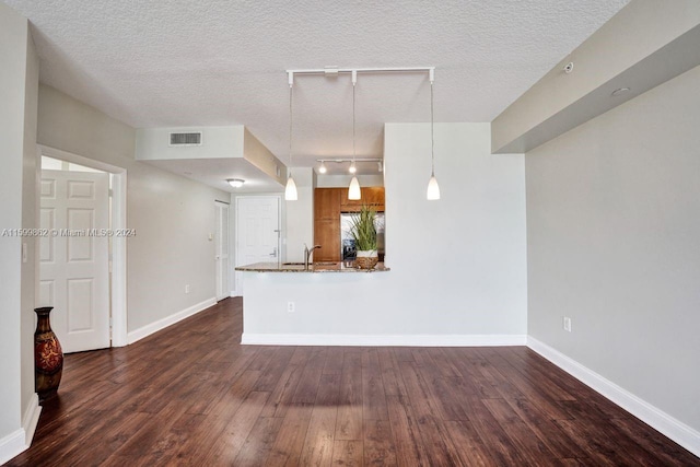 unfurnished living room featuring sink, track lighting, dark hardwood / wood-style floors, and a textured ceiling