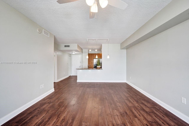 unfurnished living room featuring ceiling fan, rail lighting, dark wood-type flooring, and a textured ceiling