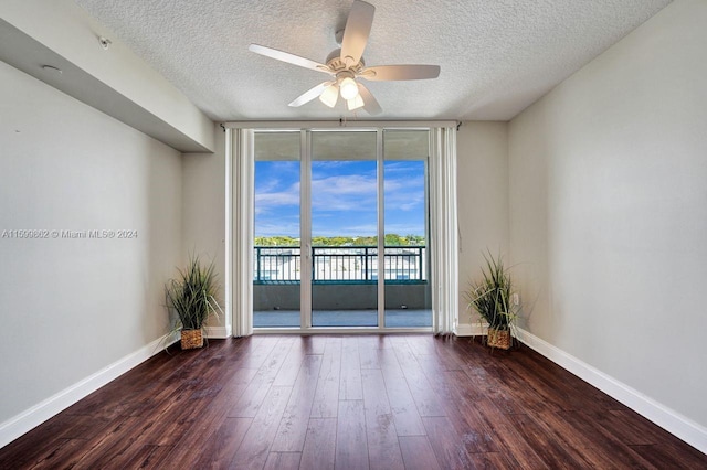 unfurnished room featuring expansive windows, ceiling fan, dark hardwood / wood-style flooring, and a textured ceiling