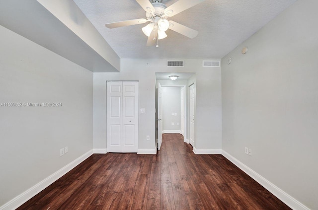 unfurnished bedroom with ceiling fan, dark wood-type flooring, a closet, and a textured ceiling