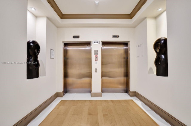 hallway with crown molding, elevator, and light tile patterned floors