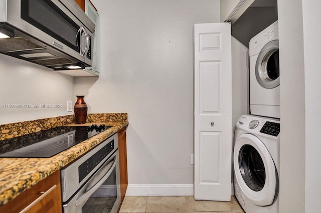 laundry area featuring light tile patterned flooring and stacked washer and clothes dryer