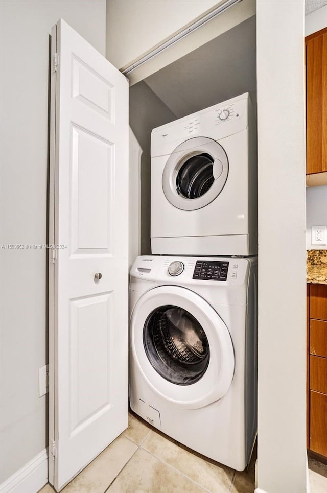 laundry room with stacked washer and dryer and light tile patterned floors