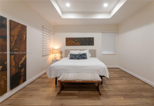 bedroom featuring a tray ceiling and light hardwood / wood-style flooring