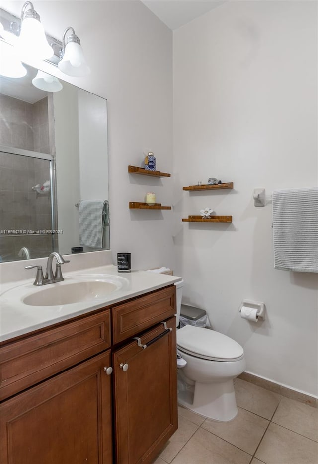 bathroom with tile patterned flooring, vanity, a shower with shower door, and toilet