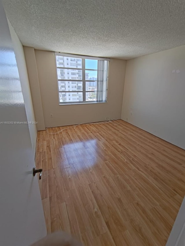 empty room with hardwood / wood-style flooring and a textured ceiling