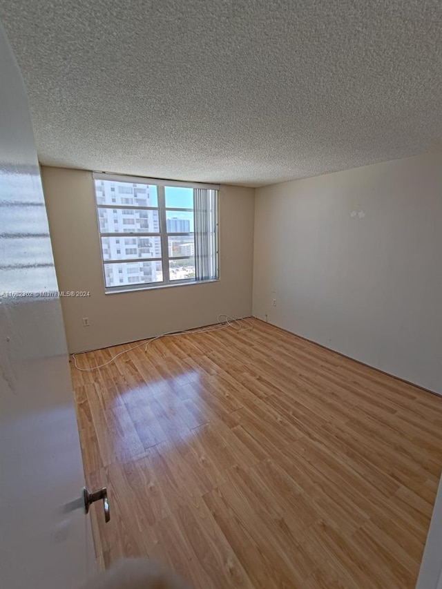 unfurnished room featuring wood-type flooring and a textured ceiling