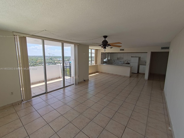 unfurnished living room featuring floor to ceiling windows, ceiling fan, light tile patterned floors, and a textured ceiling