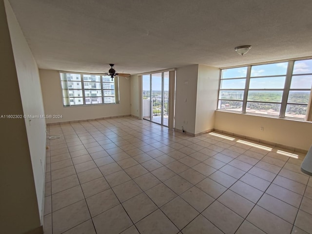 spare room with plenty of natural light, ceiling fan, light tile patterned floors, and a textured ceiling