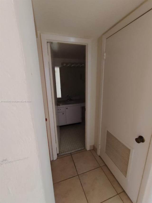 corridor featuring light tile patterned floors and sink