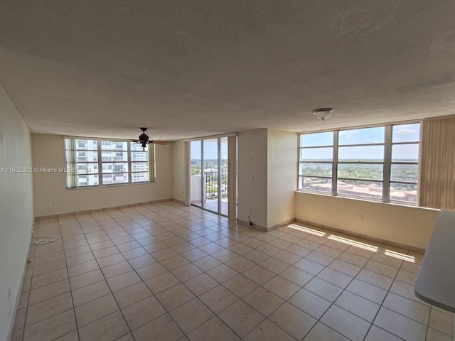 spare room with a textured ceiling, ceiling fan, a healthy amount of sunlight, and light tile patterned flooring