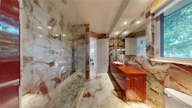 bathroom with vanity, toilet, an enclosed shower, and tile walls