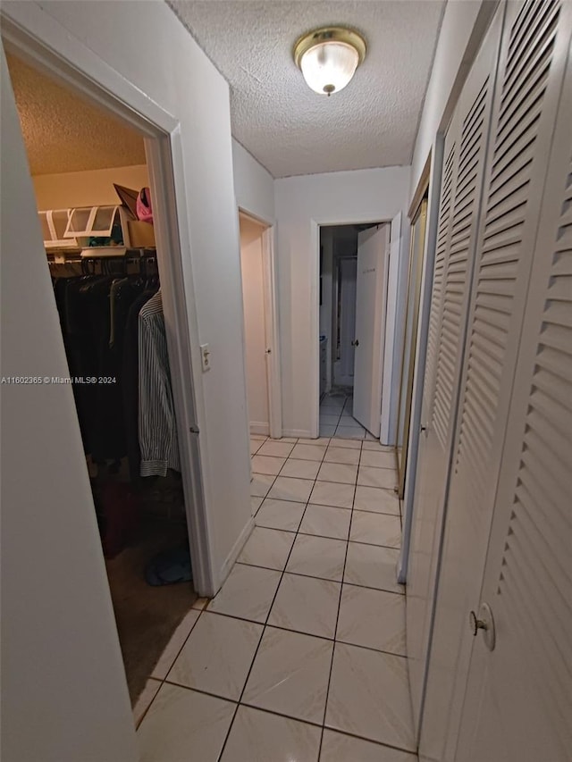 corridor featuring light tile patterned floors and a textured ceiling