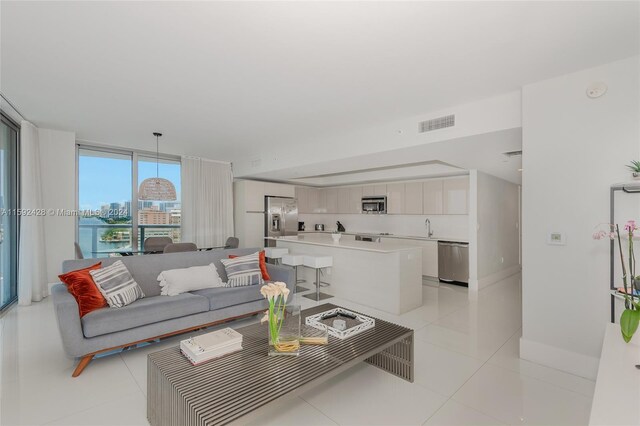 living room featuring light tile patterned floors, a wall of windows, a view of city, and visible vents