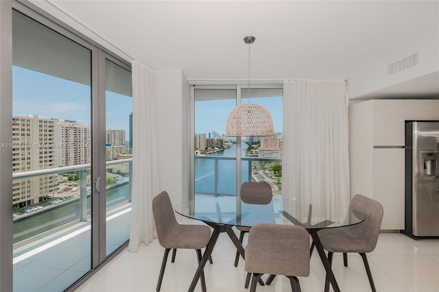 dining area with a view of city, visible vents, a wall of windows, and light tile patterned flooring