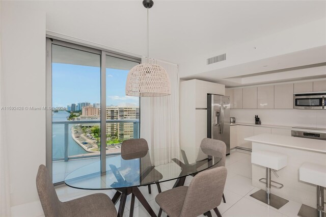 dining room featuring expansive windows, visible vents, a city view, and light tile patterned floors