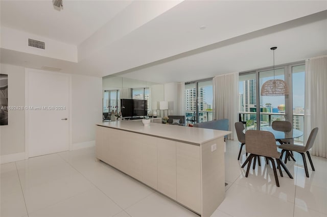 kitchen with light tile patterned floors, visible vents, a kitchen island, modern cabinets, and baseboards