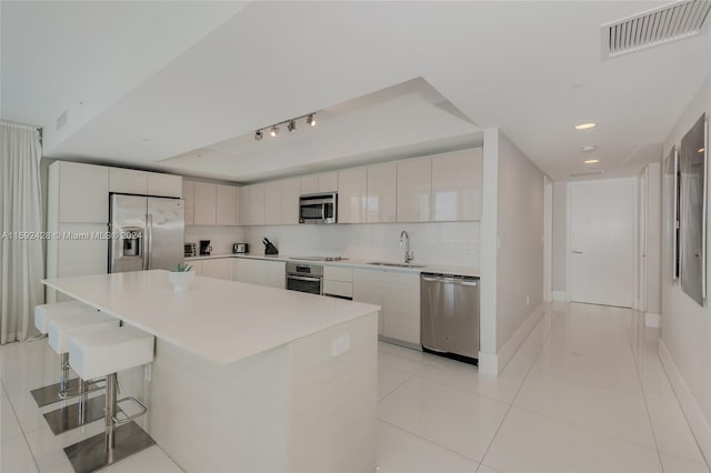 kitchen featuring visible vents, modern cabinets, appliances with stainless steel finishes, and a sink