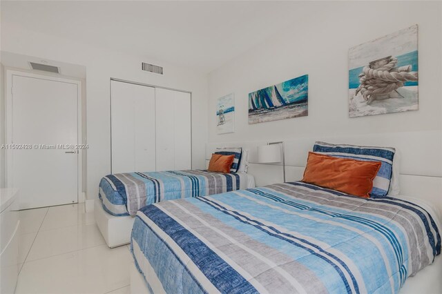 bedroom featuring tile patterned flooring, visible vents, and a closet