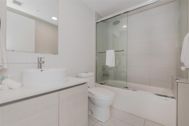 bathroom featuring visible vents, toilet, shower / bath combination with glass door, tile patterned floors, and vanity