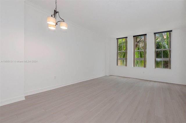 spare room featuring crown molding, a chandelier, and light hardwood / wood-style floors