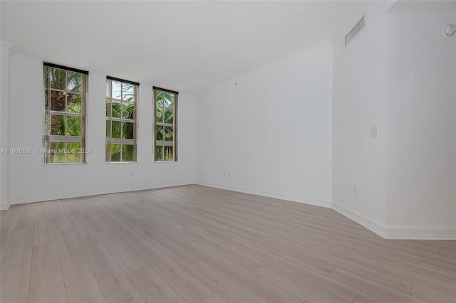 spare room with ornamental molding and light hardwood / wood-style flooring