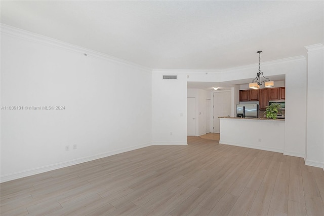 unfurnished living room with ornamental molding, an inviting chandelier, and light hardwood / wood-style flooring