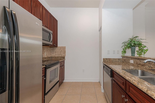 kitchen with light tile patterned floors, appliances with stainless steel finishes, stone countertops, sink, and decorative backsplash