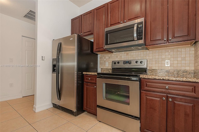 kitchen with light tile patterned floors, light stone counters, stainless steel appliances, and tasteful backsplash