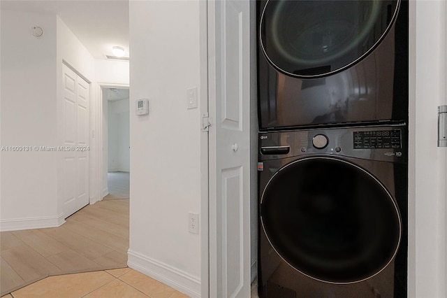 clothes washing area featuring light wood-type flooring and stacked washer / dryer