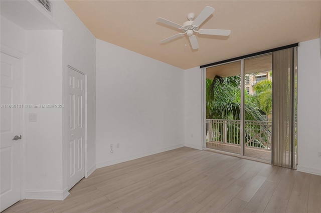 empty room with a wall of windows, ceiling fan, and light hardwood / wood-style floors