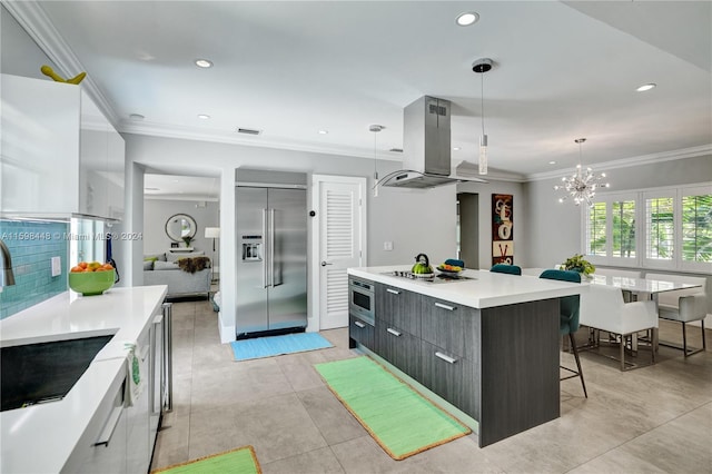 kitchen with island exhaust hood, appliances with stainless steel finishes, crown molding, a spacious island, and decorative light fixtures