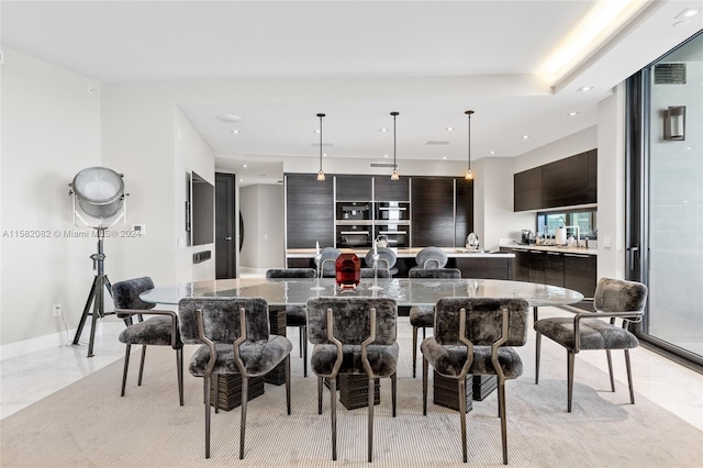 kitchen featuring decorative light fixtures, a large island with sink, dark brown cabinetry, light tile floors, and a kitchen bar