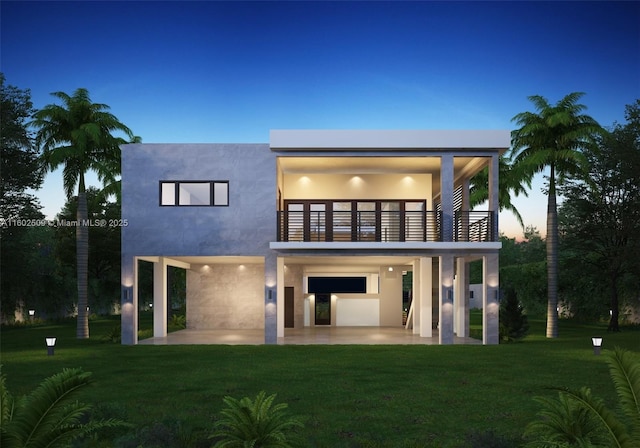 back house at dusk featuring a balcony, a yard, and a patio area