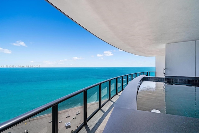 balcony featuring a view of the beach and a water view