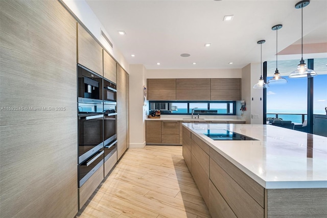 kitchen featuring decorative light fixtures, sink, black electric stovetop, wall oven, and a water view