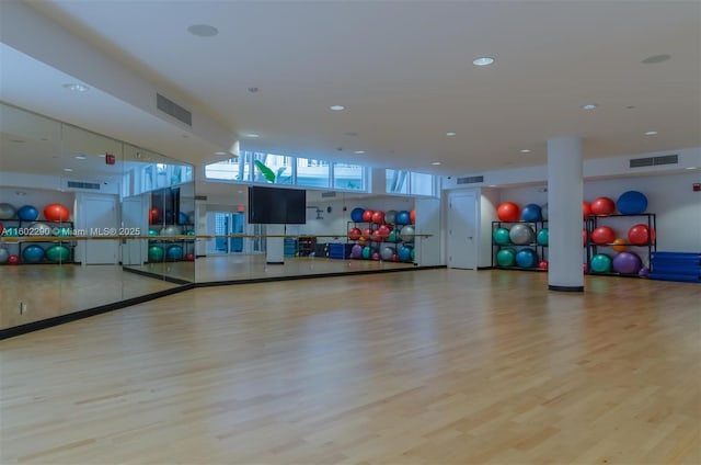 exercise room featuring light hardwood / wood-style floors and a towering ceiling