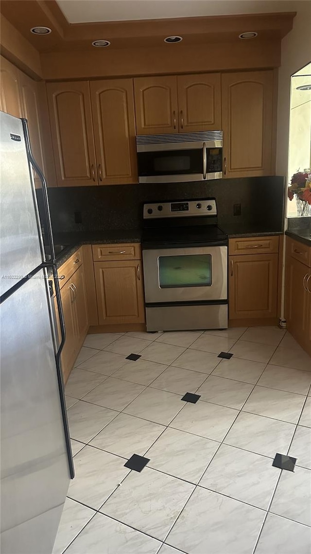 kitchen featuring stainless steel appliances, decorative backsplash, and light tile patterned floors