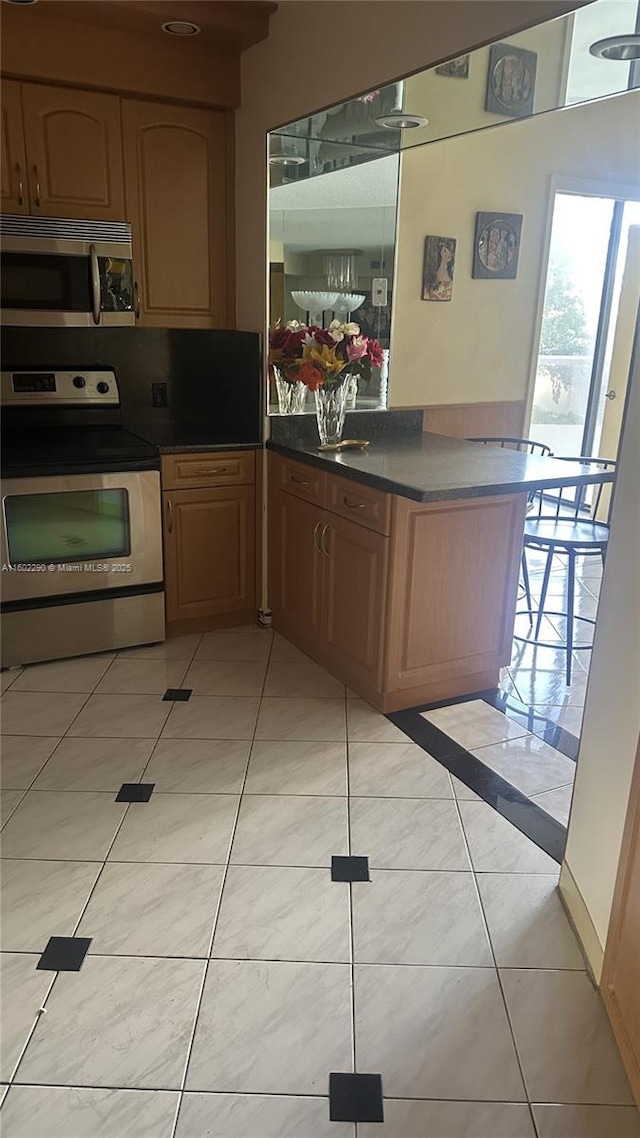 kitchen with stainless steel appliances, light tile patterned flooring, and kitchen peninsula