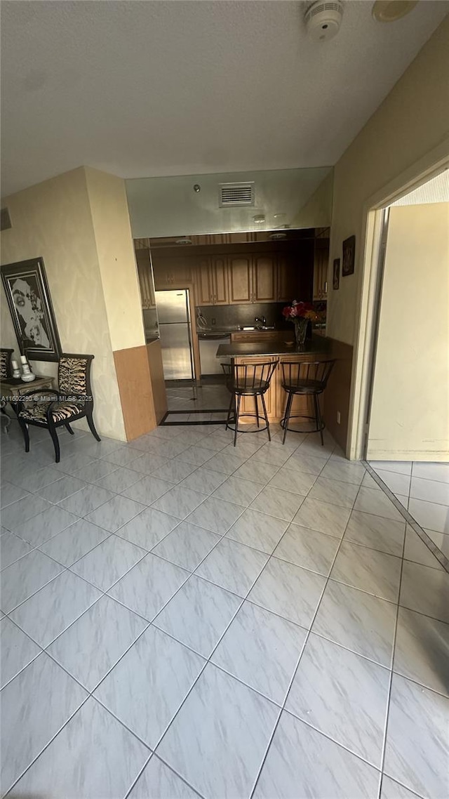 kitchen featuring a kitchen bar and stainless steel fridge